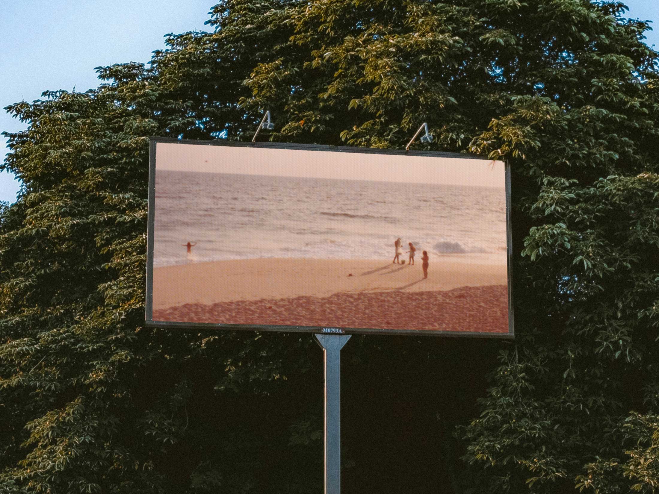 Birney-Willen, Landscapes cover artwork. Photo of a billboard in front of green leafy trees. On the billboard is a vintage photo of people on the beach in hazy sunlight.