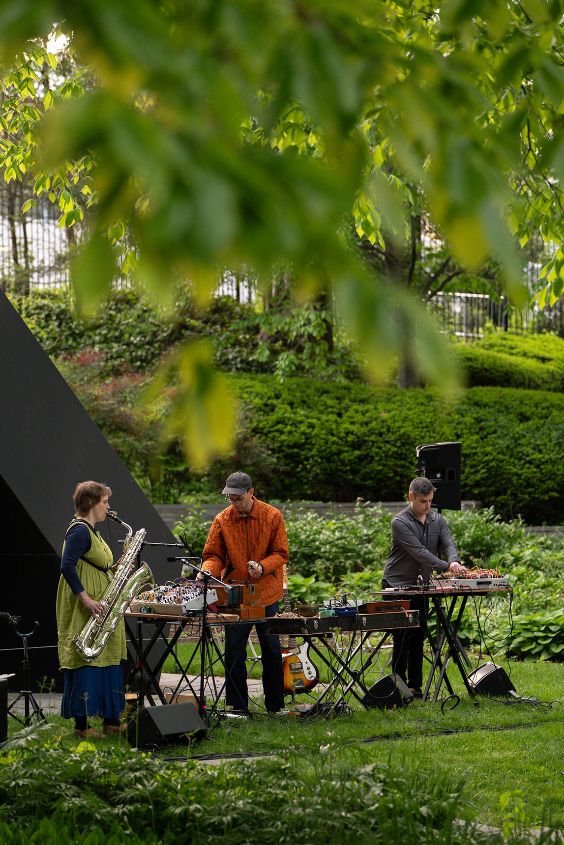 Musicians Bruce Willen, Jess Keyes, and Jason Charney performing Music for a Ghost River in the BMA Sculpture Garden surrounded by greenery